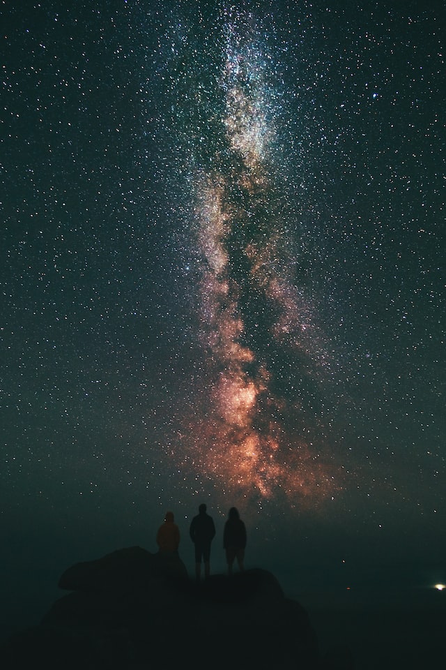 image of 3 individuals looking at cosmos in the night